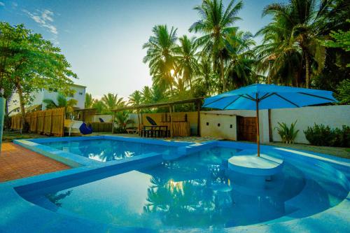 ein blauer Pool mit einem Regenschirm in der Mitte in der Unterkunft Ocean Paradise in Barra de Santiago