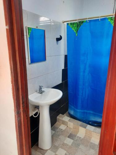 a bathroom with a sink and a blue shower curtain at Granja Don Fabio in Lemos