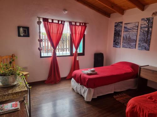 a bedroom with a red bed and a window at Casa Rural Bella Zaira in El Calafate