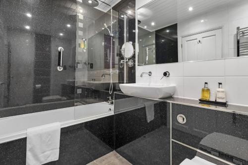 a black and white bathroom with a sink and a shower at Ravilious in Eastbourne