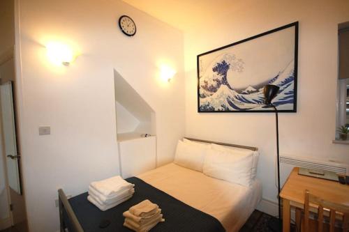 mały pokój z łóżkiem i zegarem na ścianie w obiekcie Corbyn Street Flat 2 w Londynie