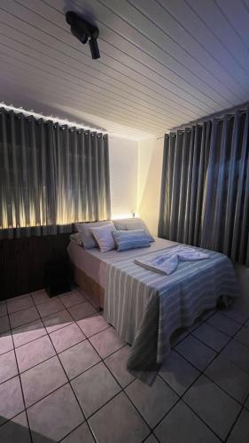 a bedroom with a bed in a room with curtains at Pousada Sol e Mar in Farol de Santa Marta