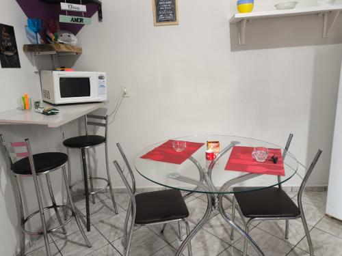 a kitchen with a table with chairs and a microwave at Kitnet Aconchegante in Foz do Iguaçu