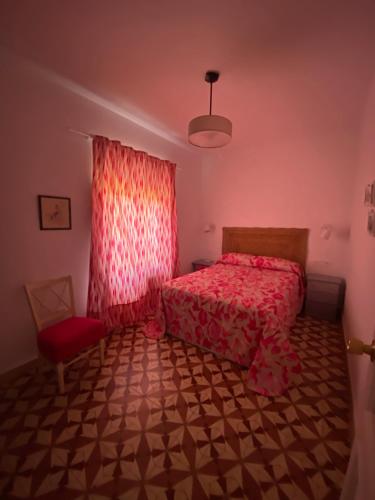 a bedroom with a red bed and a window at La casa de Alejandra, planta alta. in Perales del Puerto
