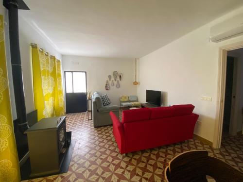 een woonkamer met een rode bank en een tv bij La casa de Alejandra, planta alta. in Perales del Puerto