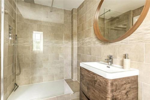 a bathroom with a sink and a tub and a mirror at Old Lodge Cottage, dog friendly and rural in Kempley