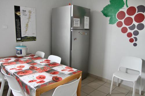 uma sala de jantar com uma mesa e um frigorífico em AUBERGE DE JEUNESSE em Colmar