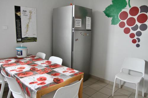 una sala da pranzo con tavolo e frigorifero di AUBERGE DE JEUNESSE a Colmar