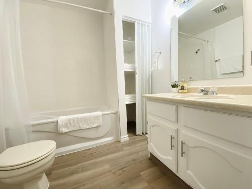 a white bathroom with a toilet and a sink at Lovely 3 bedrooms 2 bathrooms fourplex near Calgary Downtown in Calgary