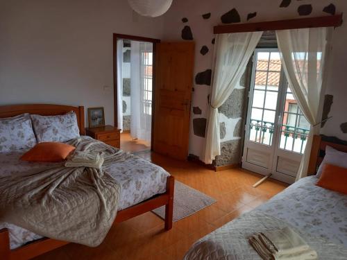 a bedroom with two beds and a door with windows at A Casa do Jesus AL in Lomba