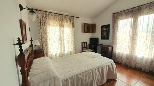 a bedroom with a bed and two large windows at Las Candelas in Casas de los Pinos