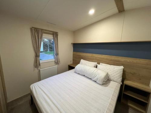 a bedroom with a bed with white sheets and a window at Laguna- Rockley Park Poole in Poole