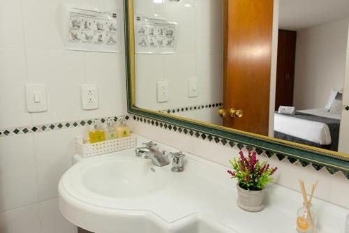 een badkamer met een wastafel en een spiegel bij Hotel Regine's Manizales in Manizales