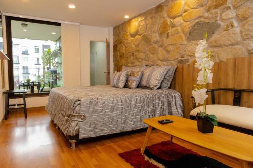 Hotel Regine's Manizales في مانيزاليس: غرفة نوم بسرير وجدار حجري