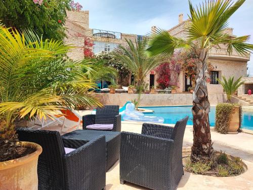 a patio with wicker chairs and a swimming pool at Dar Volubilis spacieuse villa avec piscine, 5 chambres vue sur forêt in Essaouira