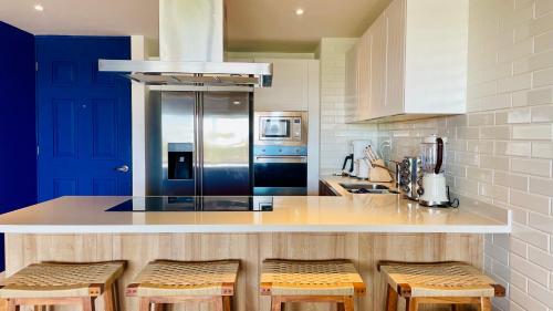 a kitchen with a counter with stools and a refrigerator at Cozy Terrace @ Blue House in Puerto Aventuras