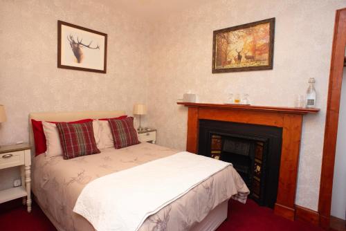 um quarto com uma cama e uma lareira em Dunvegan Bed & Breakfast em Dufftown