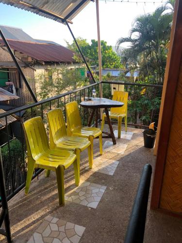 a patio with yellow chairs and a table on a balcony at Wakims INN in Coron