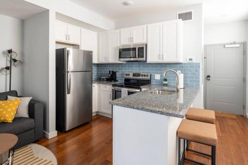 a kitchen with white cabinets and a stainless steel refrigerator at OTR, QUEEN Bed, 50in TV, Workspace, Near Lightrail in Cincinnati