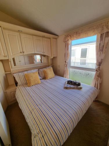 ein Bett in einem Schlafzimmer mit einem großen Fenster in der Unterkunft Dog Friendly Caravan Heacham Norfolk Holiday in Heacham