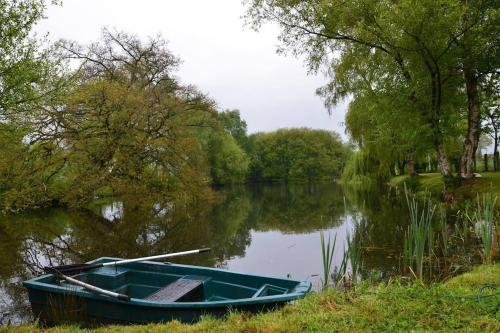 a green boat sitting on the side of a lake at Magnificent 18th Century, 5 Star Luxury Spa in Melleray-la-Vallée