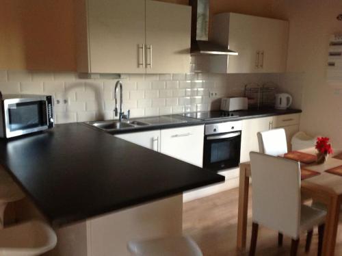 a kitchen with a black counter top and white cabinets at Magnificent 18th Century, 5 Star Luxury Spa in Melleray-la-Vallée