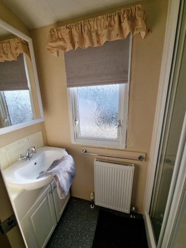 een badkamer met een wastafel en een raam bij Dog Friendly Caravan Heacham Norfolk Holiday in Heacham