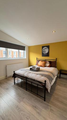 sypialnia z dużym łóżkiem z żółtymi ścianami w obiekcie 15 min to Central London Guest Suites 22 w Londynie