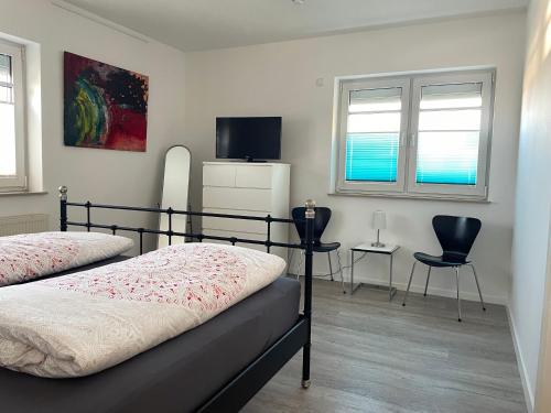 a bedroom with two beds and a tv and two chairs at Ferienwohnung Hospitalgraben in Weimar