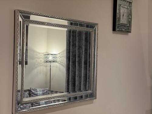 un espejo colgado en una pared junto a una lámpara en Love a staycation 2 bed apartment, en Maidenhead