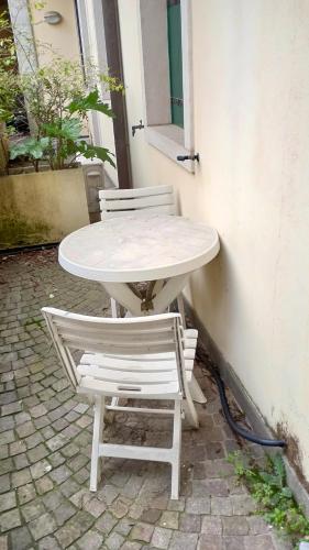 un tavolo bianco e due sedie sedute accanto a un edificio di Alloggio Turistico Artu' a Rovigo
