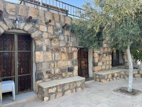 a stone building with two benches and a tree at Heritige Inn Jordan in Ad Dimnah
