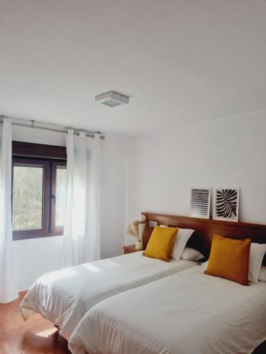 a bedroom with a large white bed with yellow pillows at La Paserina in Arenas de Cabrales