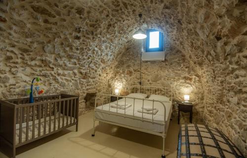 a room with a crib and a tv in a stone wall at To PAPPOUDIKO CHIOS in Chios