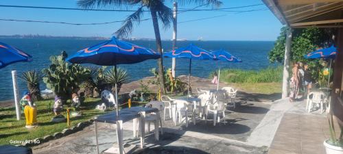 eine Terrasse mit Stühlen, Sonnenschirmen und dem Meer in der Unterkunft Pousada do Farol Bar e Restaurante in Vila Velha