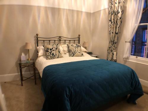 a bedroom with a bed with a blue blanket and a window at Tarn Hows in Keswick