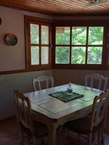 jadalnia ze stołem, krzesłami i oknami w obiekcie Hospedaje BRC w mieście Bariloche