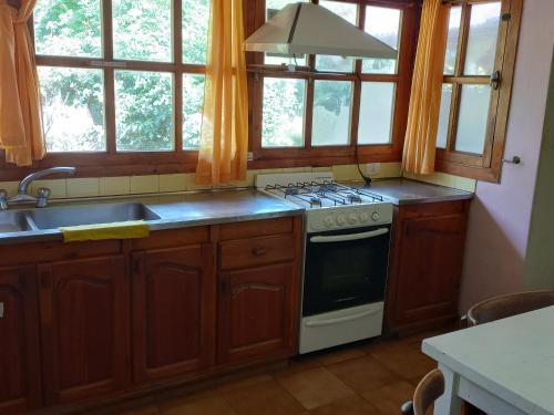 a kitchen with a stove and a sink and windows at Hospedaje BRC in San Carlos de Bariloche