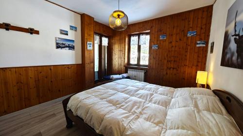 una camera con un grande letto in una stanza con pareti in legno di Hostdomus - Seguret a Cesana Torinese