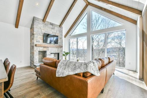- un salon avec un canapé en cuir et une cheminée dans l'établissement The Glam Shack - Golf, Ski, Spa, à Saint-Faustin–Lac-Carré