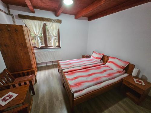 - une chambre dotée d'un lit avec des draps rayés rouges et blancs dans l'établissement Csalóka kulcsosház, à Harghita-Băi