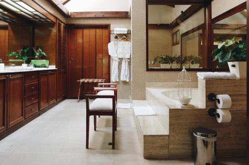 a bathroom with a sink and a tub and a chair at Sazagua Hotel Boutique in Pereira