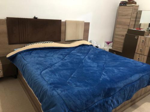 Una cama con una manta azul encima. en Family House en Al Azraq ash Shamālī
