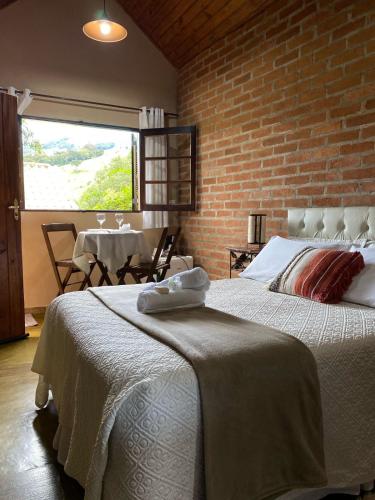 a bedroom with two beds and a brick wall at Pousada Refugio Sol e Brisa in São Bento do Sapucaí