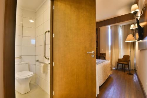 baño con aseo y 1 cama en una habitación en Pousada Stillo Gramado Exclusive en Gramado