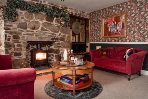 a living room with a stone fireplace and red furniture at Luxury 3 Bedroom Cottage - Sleeps 6 in Tomintoul