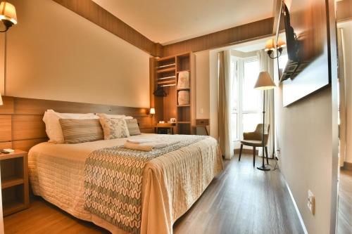 - une chambre avec un lit, une chaise et une fenêtre dans l'établissement Pousada Stillo Gramado Exclusive, à Gramado