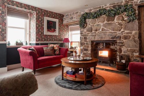 a living room with a stone fireplace and red chairs at Luxury 3 Bedroom Cottage - Sleeps 6 in Tomintoul