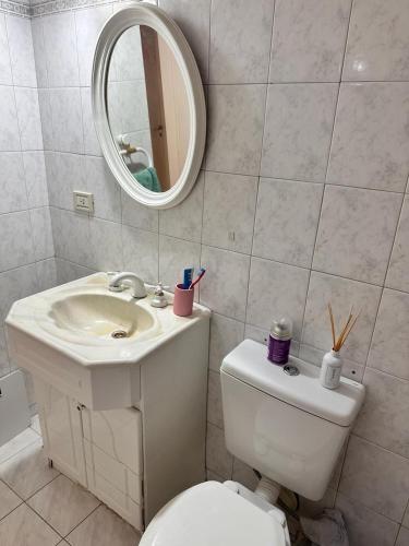 ein Badezimmer mit einem WC, einem Waschbecken und einem Spiegel in der Unterkunft Apart vista al Mar in Comodoro Rivadavia