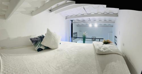 a white bedroom with a large white bed with pillows at Apartment with loft in Altos del Maria in Sorá